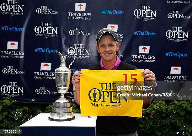 Luke Donald of England holds a hole flag and stands next to the Open Championship Trophy after qualifying for the Open Championship during the final...