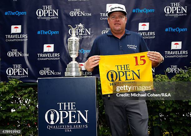 Carl Pettersson of Sweden holds a hole flag and stands next to the Open Championship Trophy after qualifying for the Open Championship during the...