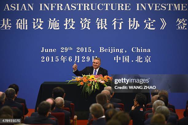 Australia's Treasurer Joe Hockey holds up his pen as he becomes the first to sign an articles of association to help set up the Asian Infrastructure...