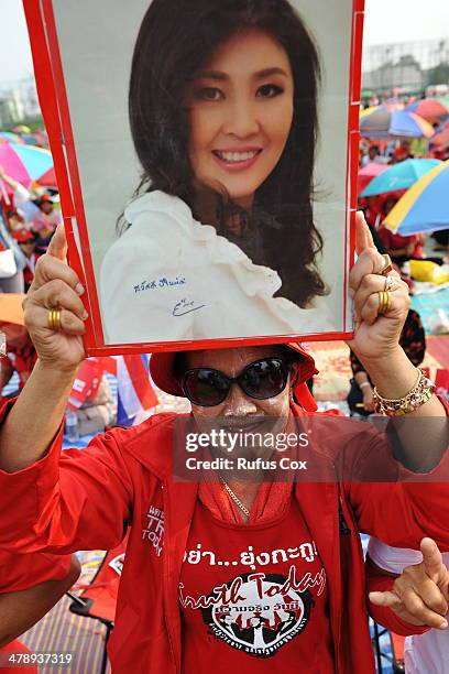 Pro-government red shirt supporter holds up a portrait of caretaker Prime Minister Yingluck Shinawatra at a large rally on March 15, 2014 in...