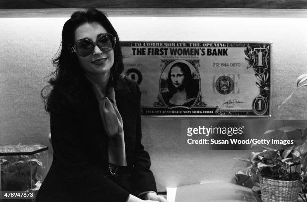 American businesswoman, politician, and activist Eileen Preiss poses in front of a poster advertisement of a dollar bill at Manhattan's First Women's...