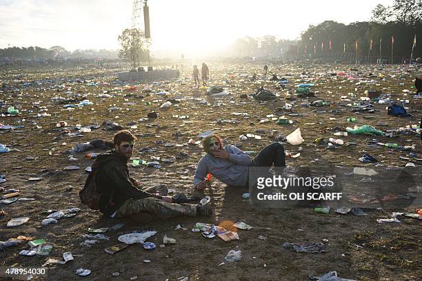 Revellers rest on the ground surrounded by discarded litter at the Glastonbury Festival of Music and Performing Arts on Worthy Farm near the village...