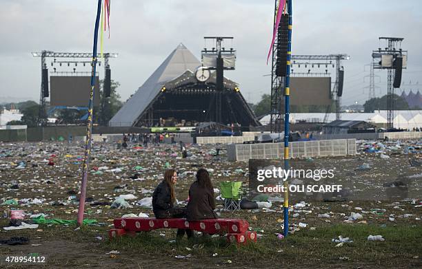 Revellers are pictured in front of the Pyramid Stage surrounded by discarded litter at the end of the Glastonbury Festival of Music and Performing...