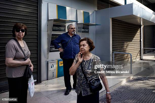 Pensioners stand outside of a branch of the National Bank of Greece hoping to draw their pensions on June 29, 2015 in Athens, Greece. Greece closed...