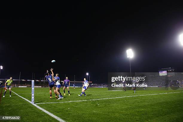 Richard Kennar of the Storm jumps to kicks a kick under pressure from Curtis Rona of the Bulldogs during the round 16 NRL match between the...