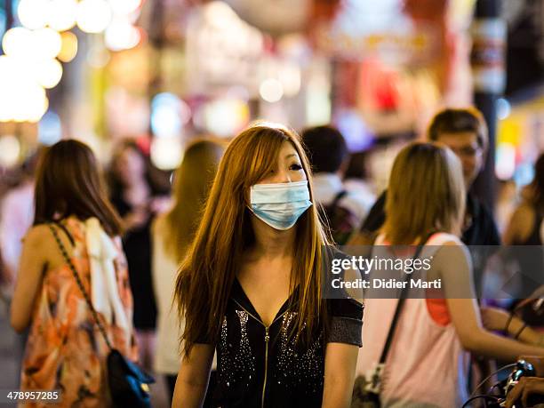 Attractive young woman wear a face mask at night in the streets of Osaka in Japan