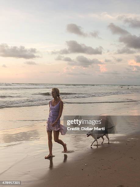 Woman walking the dog on the beach in Bali