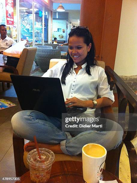 Young indonesian woman using a laptop computer in a coffeshop in bali