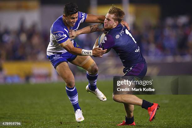 Tim Lafai of the Bulldogs tackles Cameron Munster of the Storm during the round 16 NRL match between the Canterbury Bulldogs and the Melbourne Storm...