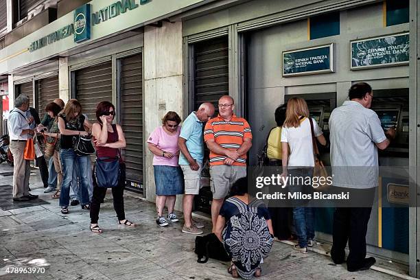 People wait in line to withdraw 60 euros from an ATM after Greece closed its banks on June 29, 2015 in Athens, Greece. Greece closed its banks and...