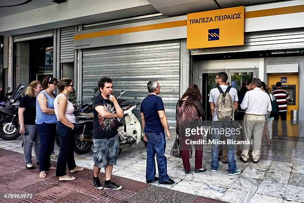People wait in line to withdraw 60 euros from an ATM after Greece closed its banks on June 29, 2015 in Athens, Greece. Greece closed its banks and...
