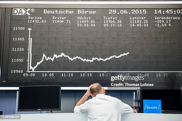 Trader stands under the day's performance graph showing a sharp drop of the German DAX stock market index early today and a partial recovery later on...