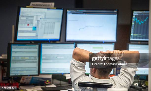 Trader looks at computer screens as the day's performance graph showed a sharp drop of the German DAX stock market index early today and a partial...