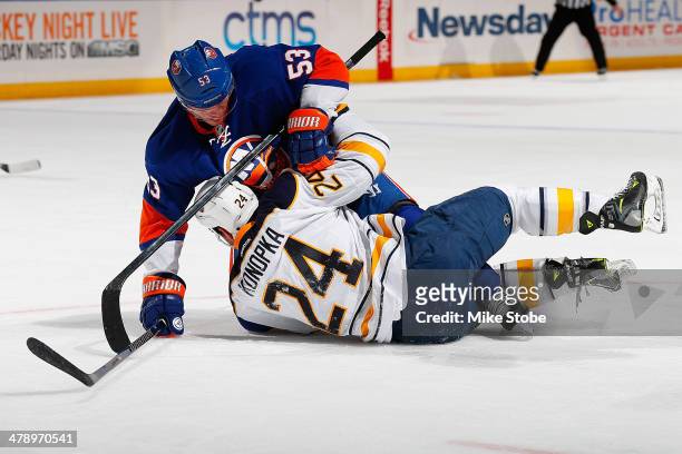 Casey Cizikas of the New York Islanders and Zenon Konopka of the Buffalo Sabres fall to the ice battling for position at Nassau Veterans Memorial...