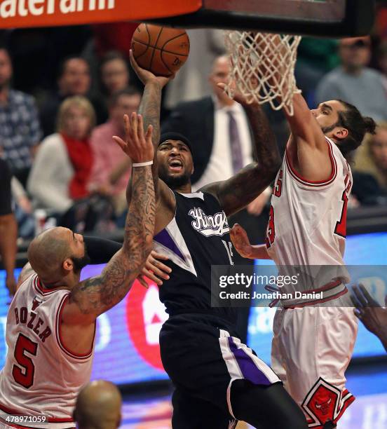 DeMarcus Cousins of the Sacramento Kings shoots between Carlos Boozer and Joakim Noah of the Chicago Bulls at the United Center on March 15, 2014 in...