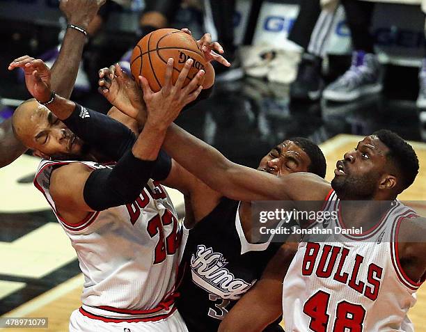 Taj Gibson of the Chicago Bulls rebounds over teammate Nazr Mohammed and Jason Thompson of the Sacramento Kings at the United Center on March 15,...