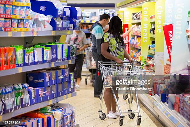 Customer pushes a shopping cart as they walk through the shopping aisles inside an Aldi supermarket store in London, U.K., on Monday, June 29, 2015....