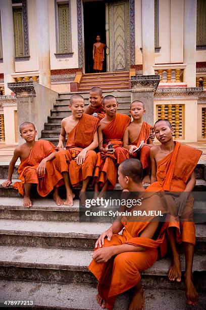 Monks sitting in front of an old monastery, Wat Slaket, in Battambang, Cambodia.