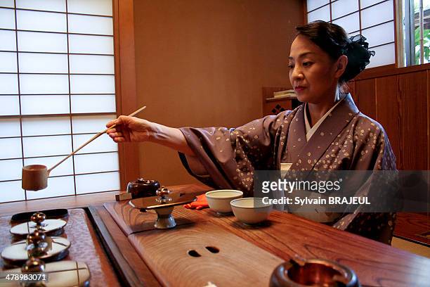 Japanese woman dressed in a kimono during a japanese traditional tea ceremony, inside a Ryokan, Kanazawa, Honshu, Japan.