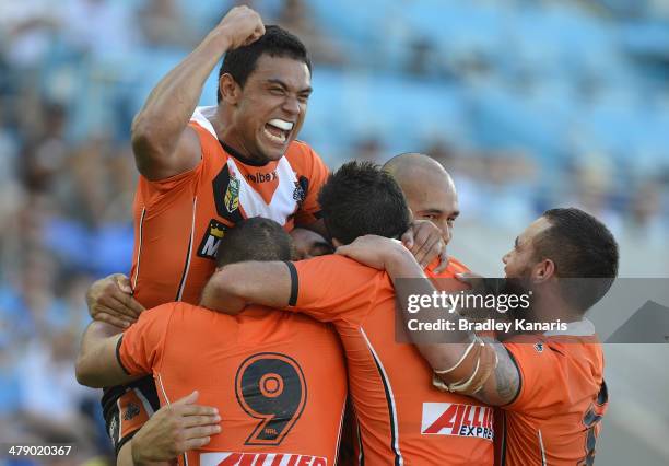 Martin Taupau of the Tigers is swamped by team mates as they celebrate his try during the round two NRL match between the Gold Coast Titans and the...