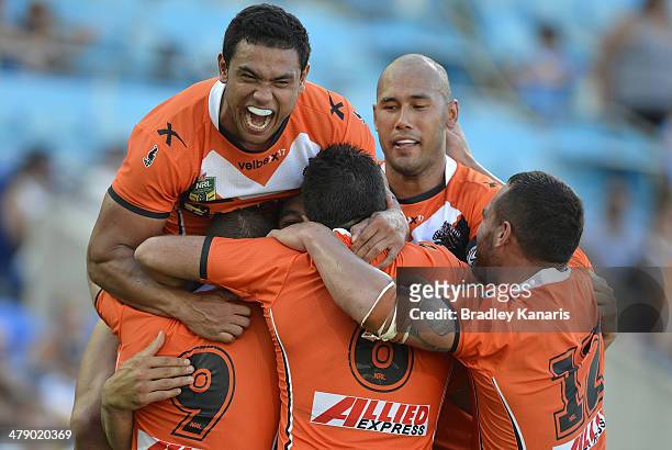 Martin Taupau of the Tigers is swamped by team mates as they celebrate his try during the round two NRL match between the Gold Coast Titans and the...