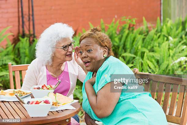 two senior women having lunch, gossiping - eating secret stockfoto's en -beelden