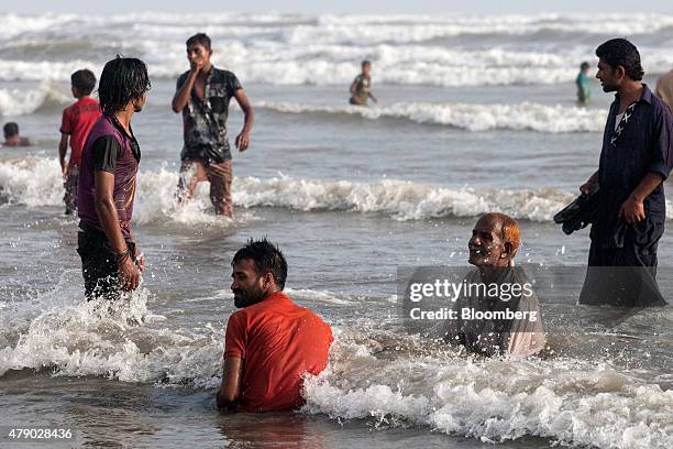 People sit and stand in the sea at Clifton Beach during a heat wave in Karachi, Pakistan on Monday, June 29, 2015. A heat wave where temperatures...