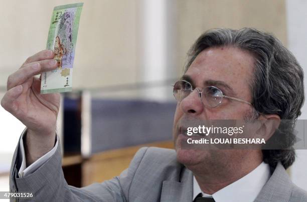 Chief of the Central Bank of Syria Adeeb Mayalah holds up a new Syrian 1000 pound bank note, on June 30 following its release by the Central Bank of...