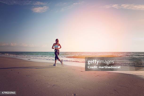 young fit woman running on the beach at sunset. - marathon florida stockfoto's en -beelden