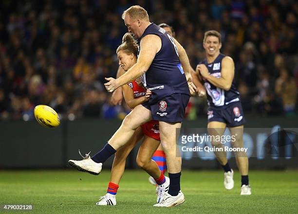Abbey Holmes of the All Stars bumps Lance Whitnall of Victoria as he kicks during the EJ Whitten Legends Game at Etihad Stadium on June 30, 2015 in...