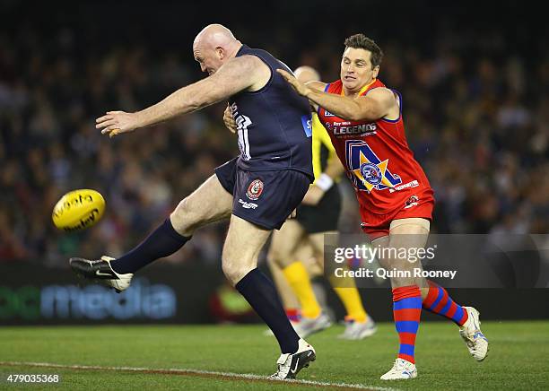 Michael Martyn of Victoria kicks whilst being tackled by Shane Crawford of the All Stars during the EJ Whitten Legends Game at Etihad Stadium on June...