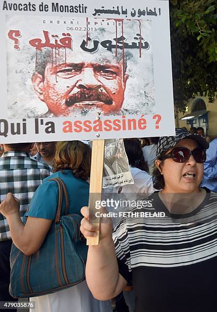 Tunisian demonstrator holds a banner in front of the court in Tunis on June 30 during the opening trial of the 24 people accused of links to the 2013...