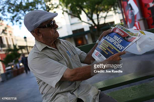 Tomas Colon reads a newspaper with a Spanish headline that reads, "more sacrifices," a day after the speech Puerto Rican Governor Alejandro Garcia...
