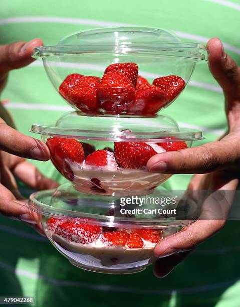 Visitor holds tubs of strawberries on day two of Wimbledon tennis tournament on June 30, 2015 in London, England. The 129th tournament to be hosted...