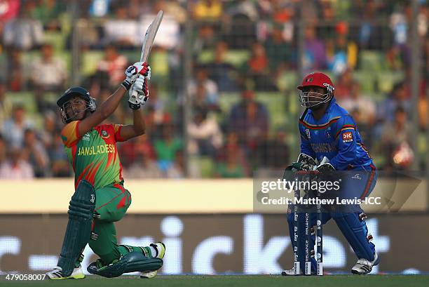 Anamul Haque of Bangladesh hits a six, as Mohammad Shahzad of Afghanistan looks on during the ICC World Twenty20 Bangladesh 2014 match between...