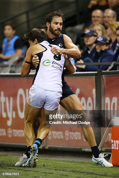 Andew Walker of the Blues throws Angus Monfries of the Power into the fence during a tackle during the round one AFL match between the Carlton Blues...