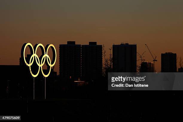 The Olympic rings are illuminated during a sunset, backdropped by apartment blocks near Stratford, inside the Olympic Park before the Revolution 5 at...