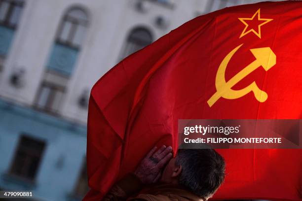 Man kisses the Soviet Union flag in Simferopol's Lenin Square on March 16, 2014. Polls opened today in a referendum on the peninsula of Crimea, in...