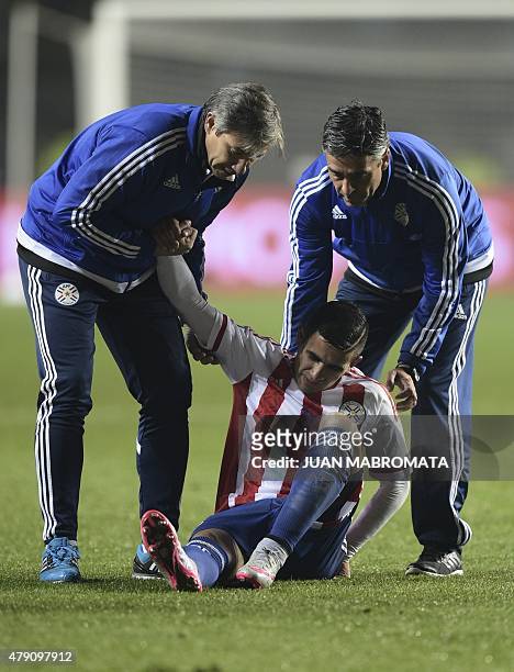 Paraguay's forward Derlis Gonzalez is helped by assistants to get up during their Copa America semifinal football match against Argentina in...