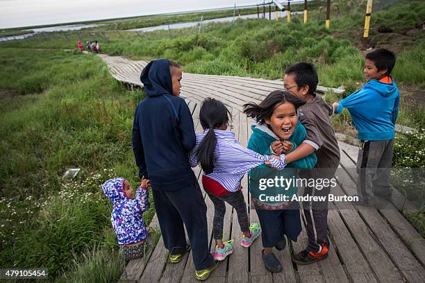 Children play a game of Red Rover along a raised wooden sidewalks - used to help stablize the ground - on June 29, 2015 in Newtok, Alaska. Newtok,...