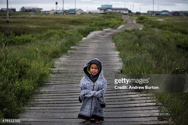 Yupik child stands on raised, wooden sidewalks, used to help cross unstable ground, on June 30, 2015 in Newtok, Alaska. Newtok, which has a...