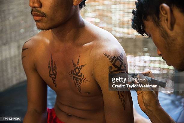 Cambodian circus artists prepare for a show by drawing on fake tattoos with marker on July 1, 2015 at Phare - The Cambodian Circus in Siem Reap,...