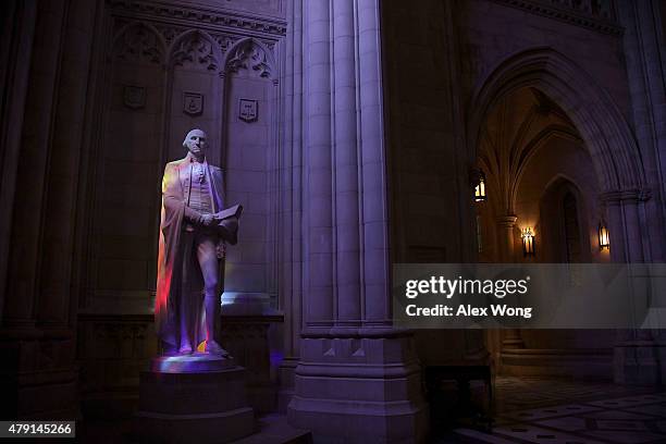 Colored lights shine through stained glass windows onto a statue of George Washington at the National Cathedral July 1, 2015 in Washington, DC. The...