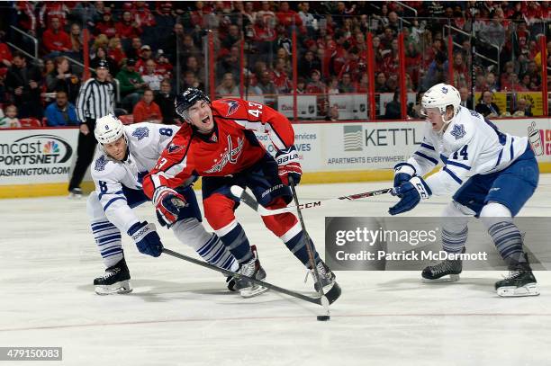 Tom Wilson of the Washington Capitals reacts as he battles for the puck against Tim Gleason and Morgan Rielly of the Toronto Maple Leafs in the...