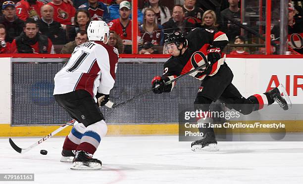 Mika Zibanejad of the Ottawa Senators shoots the puck against Andre Benoit of the Colorado Avalanche during an NHL game at Canadian Tire Centre on...