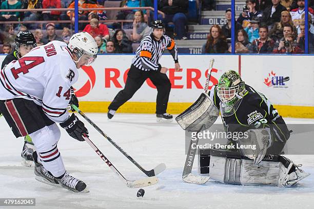 Tyler Santos of the Edmonton Oil Kings eyes the shot of Rhyse Dieno of the Red Deer Rebels during a WHL game at Rexall Place on March 16, 2014 in...