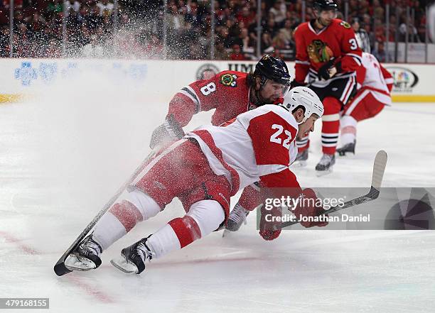 Jordin Tootoo of the Detroit Red Wings hits the ice under pressure from Nick Leddy of the Chicago Blackhawks at the United Center on March 16, 2014...