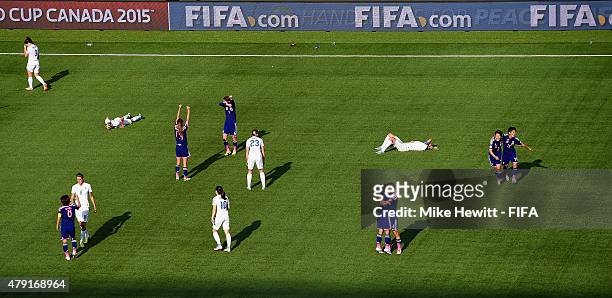 Japan players celebrate at the full time whistle as England players sink to the floor during the FIFA Women's World Cup 2015 Semi Final match between...