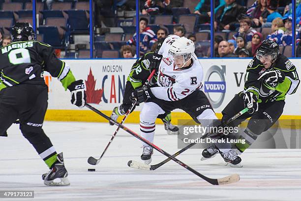 Garan Magnes and Luke Bertolucci of the Edmonton Oil Kings try to check Scott Feser of the Red Deer Rebels during a WHL game at Rexall Place on March...