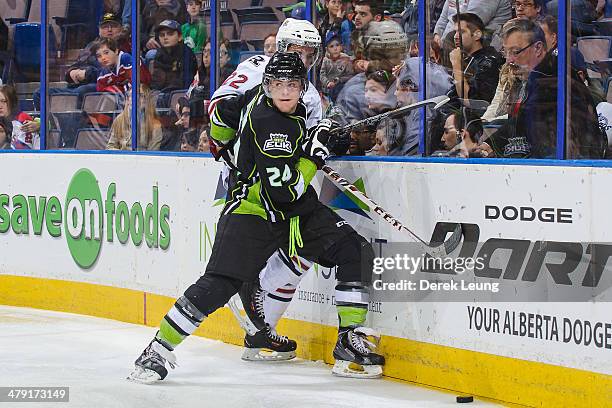 Aaron Irving of the Edmonton Oil Kings checks Scott Feser of the Red Deer Rebels during a WHL game at Rexall Place on March 16, 2014 in Edmonton,...